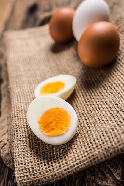 Uova di gallina bollite o crude ravvicinate su tavola di legno.