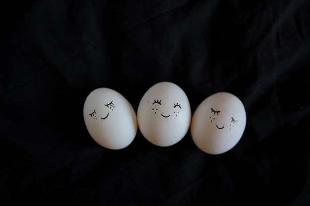 Uova di gallina con faccia dipinta su sfondo nero Uova dipinte a mano Uova di Pasqua naturali