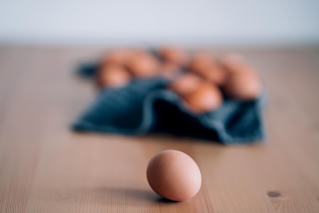 Uova di gallina crude sull'asciugamano sulla tavola di legno. Un uovo marrone fresco in primo piano. Alimenti biologici ad alto contenuto proteico per una buona salute, prodotti agricoli. Messa a fuoco selettiva.