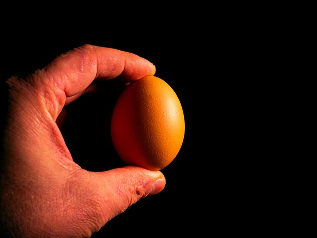 Uova di gallina di Pasqua in mano su uno sfondo nero
