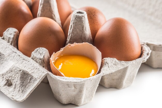 Uova di gallina fresche in vassoio pater con uovo rotto.