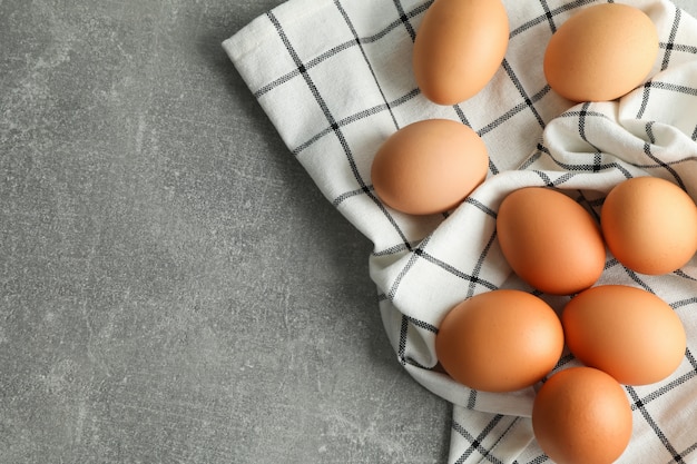 Uova di gallina in asciugamano da cucina su grigio