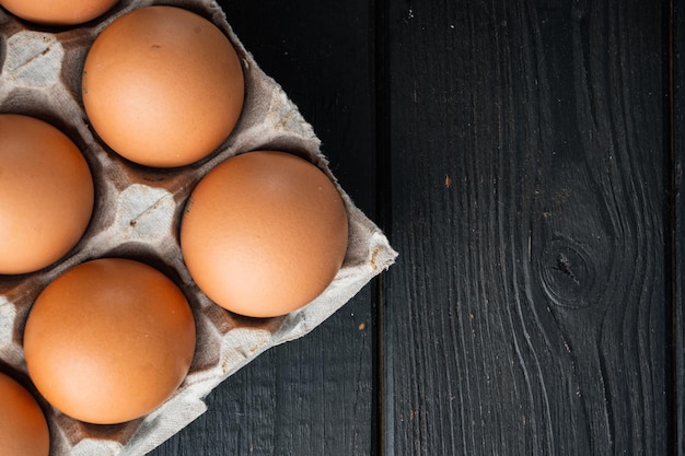 Uova di gallina in un set di vassoi per uova, su sfondo di tavolo in legno nero, vista dall'alto piatta, con spazio per copyspace di testo