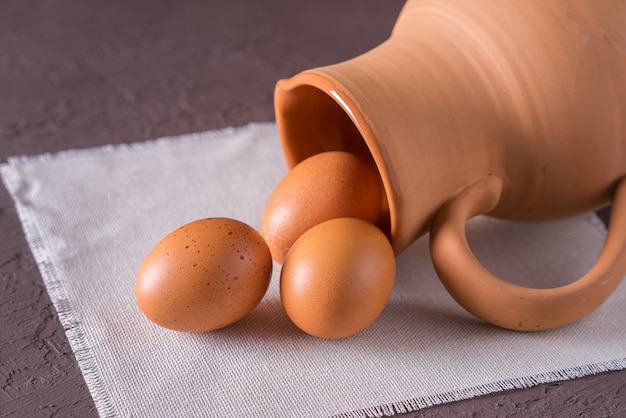 Uova di gallina in una brocca di argilla su un tovagliolo di lino