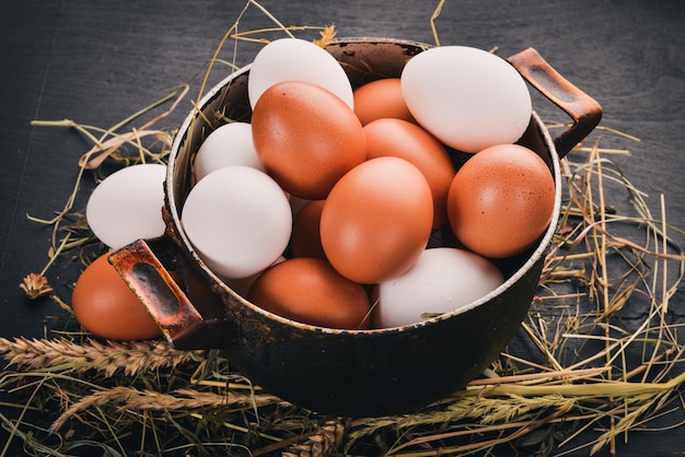 Uova di gallina in una casseruola di metallo su uno sfondo di legno Vista dall'alto Copia spazio