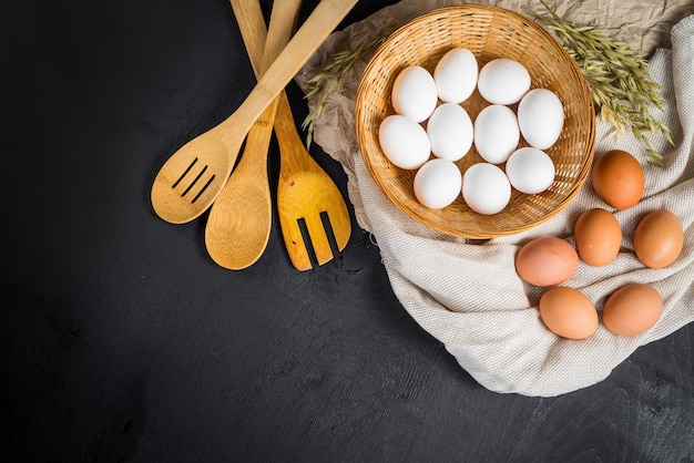 Uova di gallina nel cestino su fondo di legno nero. Copia spazio