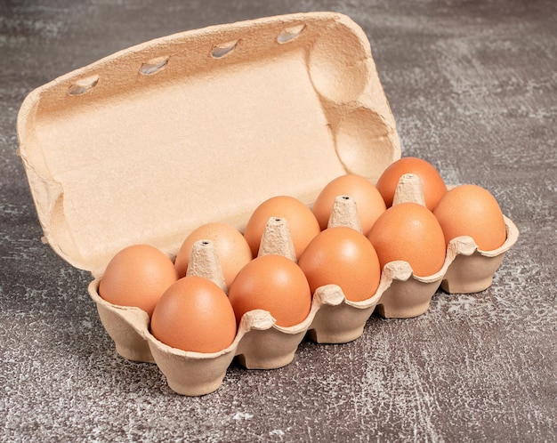 Uova di gallina organiche fresche in confezione di cartone aperta o contenitore per uova su sfondo marrone