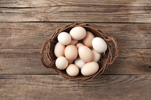 Uova di gallina organiche in cestino su fondo di legno. Concetto di famiglia biologica con uova di galline allevate a terra e al pascolo