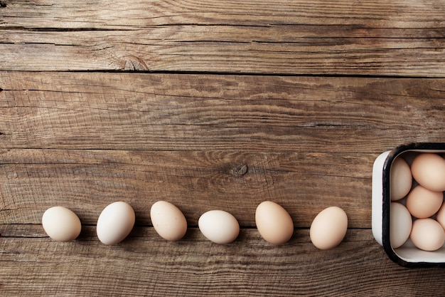 Uova di gallina organiche in scatola di metallo su fondo di legno di fila. Concetto di famiglia biologica con uova di galline allevate a terra e al pascolo