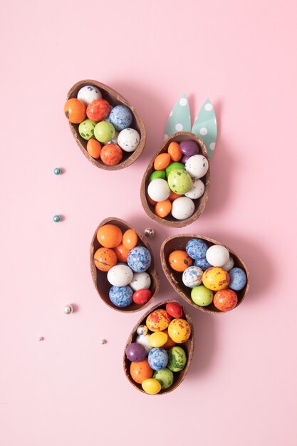 Uova di Pasqua al cioccolato e decorazioni piatte per bambini concetto di uova di caccia di Pasqua su sfondo rosa Dolci a forma di uovo