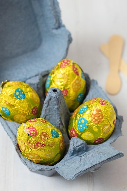 Uova di Pasqua al cioccolato in una scatola di uova di cartone su un tavolo bianco