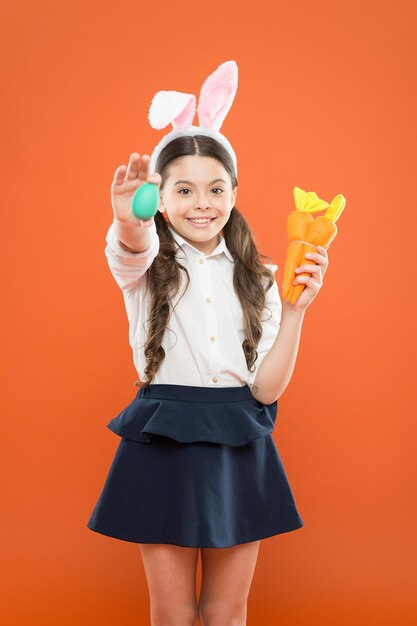 Uova di Pasqua. Buona Pasqua. Origini delle tradizioni pasquali. Orecchie da coniglietta da bambina. Ragazzo a caccia di uova di Pasqua. Adorabile bambino felice tenere le uova. Vacanze di primavera. La piccola scolara in orecchie di coniglio tiene la carota.