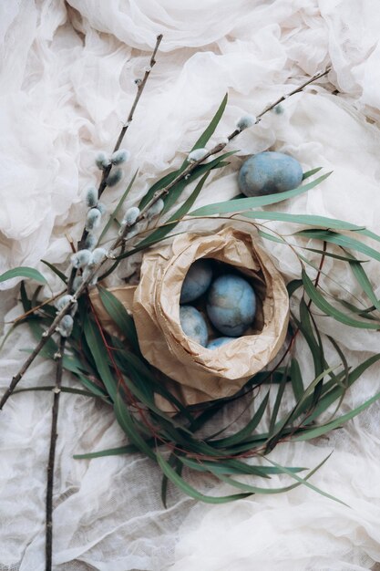 Uova di Pasqua color pastello in un piccolo cesto di vimini su sfondo chiaro Concetto minimo di celebrazione pasquale Uova di gallina tinte