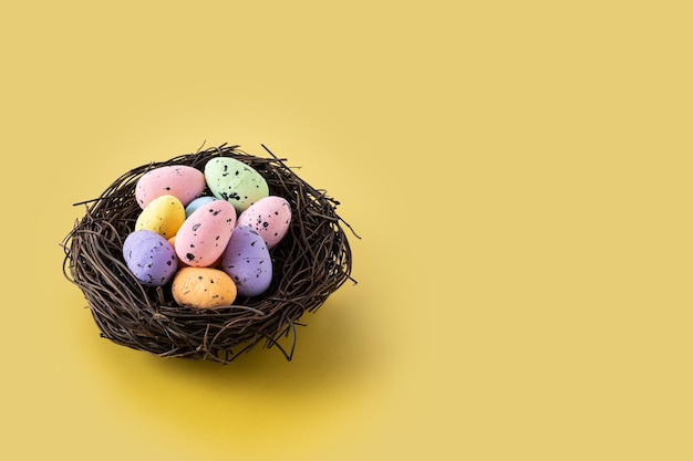 Uova di Pasqua colorate all'interno di un nido su sfondo giallo Copia spazio