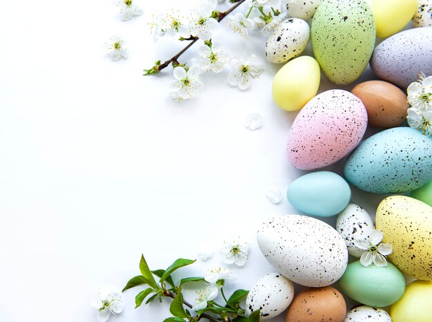 Uova di Pasqua colorate con fiori di primavera sbocciano i fiori isolati su sfondo bianco.