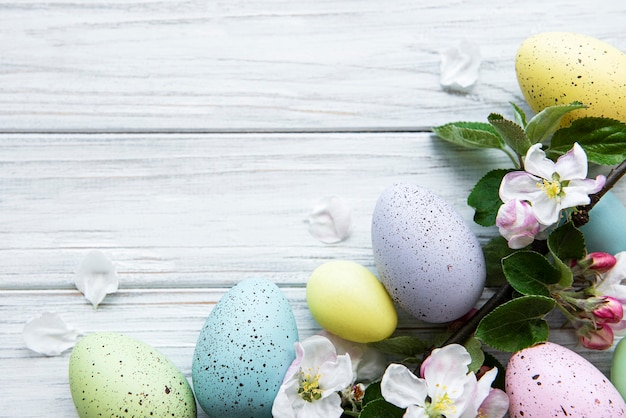 Uova di Pasqua colorate con fiori di primavera sbocciano i fiori sul tavolo di legno.