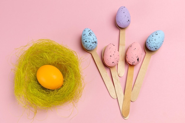 Uova di Pasqua colorate con il nido e i cucchiai di legno.