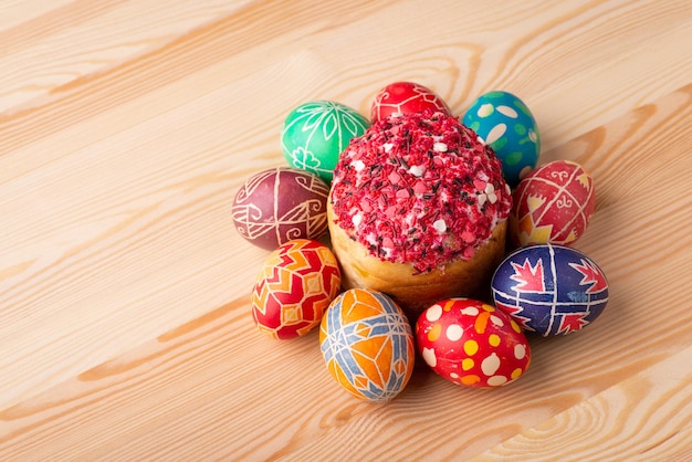Uova di Pasqua colorate con un pane di Pasqua nel mezzo sulla tavola di legno. Decorazioni pasquali, uova dipinte tradizionali per la celebrazione del tempo pasquale