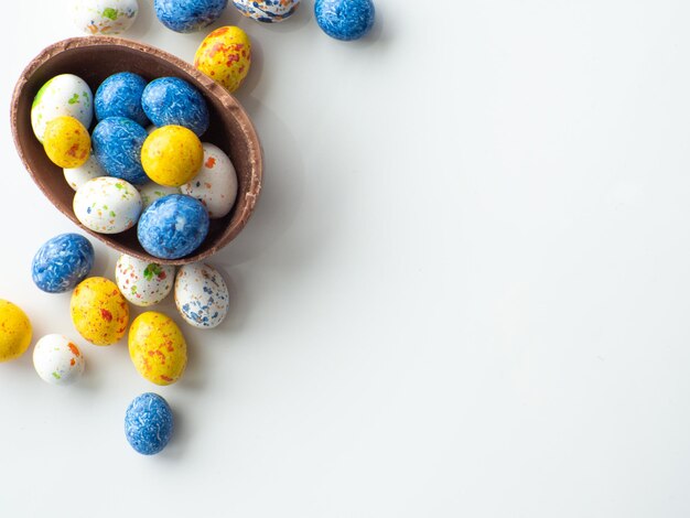 Uova di pasqua colorate e al cioccolato con confetto dolce su sfondo bianco