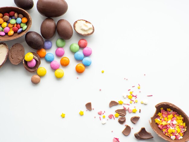 Uova di Pasqua colorate e al cioccolato con confetto dolce su sfondo bianco