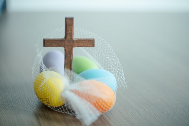 Uova di Pasqua colorate e una croce di legno mostrano i religiosi e la Pasqua a terra