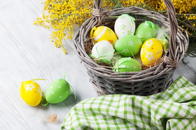 Uova di Pasqua colorate in cestino e mimosa