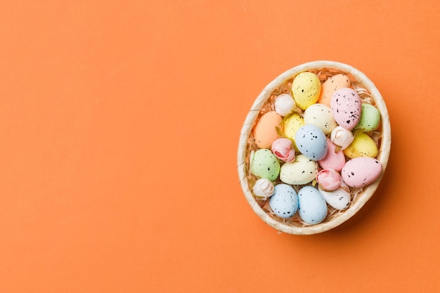 Uova di Pasqua colorate in cesto di vimini su sfondo colorato primo piano vista dall'alto con spazio di copia