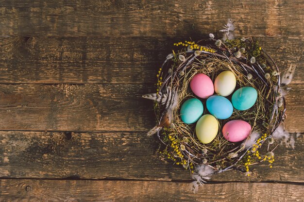 Uova di Pasqua colorate in un bellissimo nido. Sullo sfondo di una vecchia tavola di legno.