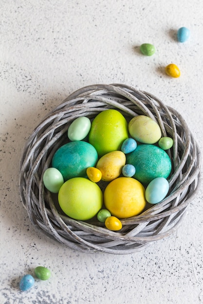 Uova di Pasqua colorate in un nido su sfondo chiaro.