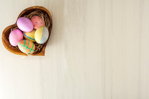 Uova di Pasqua colorate nel piatto di legno sul tavolo grigio con posto per testo, vista dall'alto