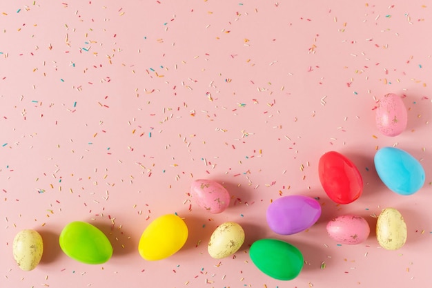 Uova di Pasqua colorate su sfondo rosa pastello vista dall'alto