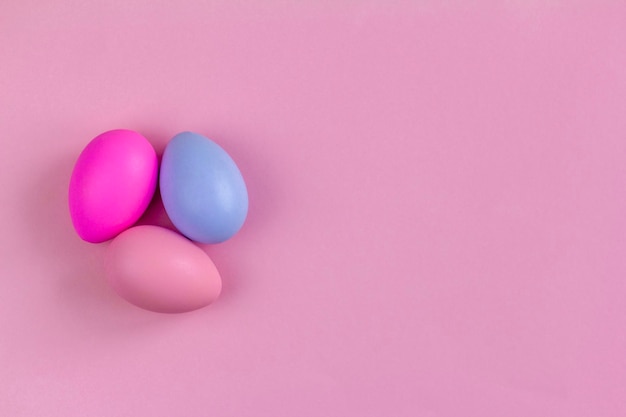 Uova di Pasqua colorate su uno sfondo rosa vista dall'alto