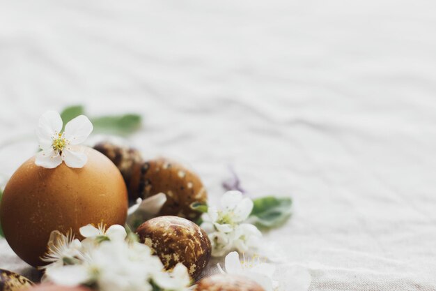 Uova di Pasqua con fiori primaverili e teneri petali su lino rustico Vacanza estetica eco naturale