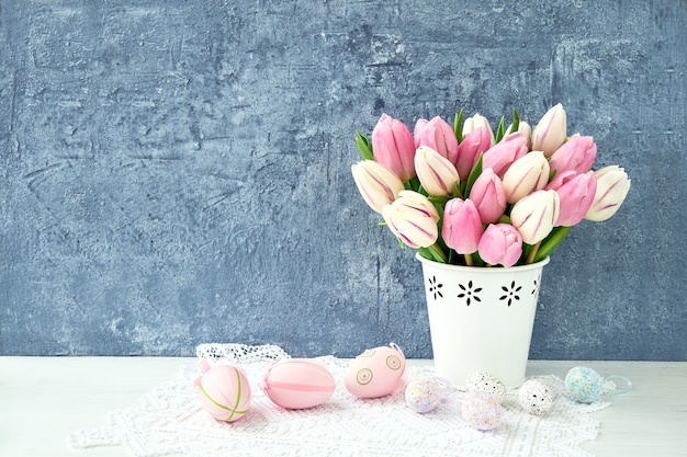 Uova di Pasqua decorative e tulipani rosa in vaso. Copia spazio