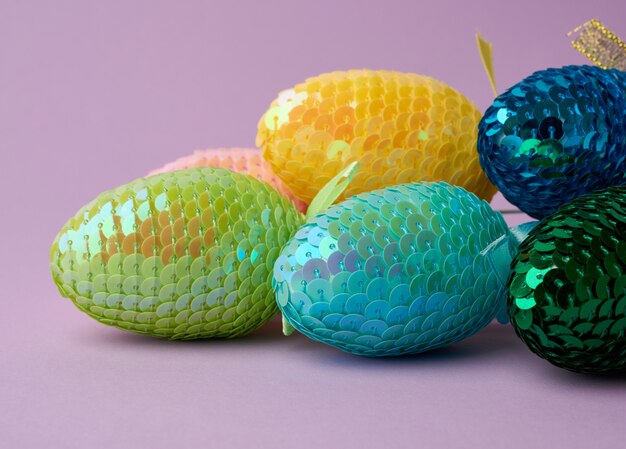 Uova di Pasqua decorative multicolori decorate con paillettes su una superficie viola