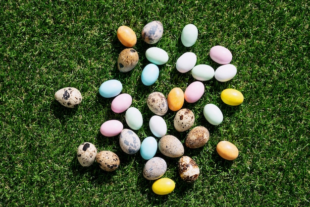 Uova di Pasqua di cioccolato glassate con coloranti pastello e uova di quaglia su erba verde. Felice Pasqua concetto. Copia spazio. Vista dall'alto