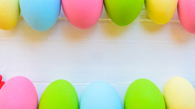 Uova di Pasqua di fila su fondo di legno bianco.