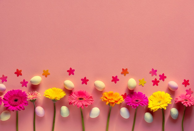 Uova di Pasqua di marzapane, fiori di gerbera, coriandoli su carta arancione