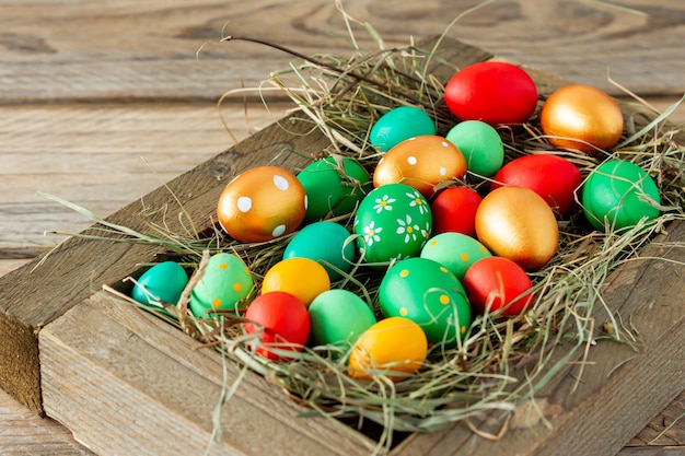 Uova di Pasqua dipinte a mano colorate in scatola di legno bianca su tavolo di legno con spazio per copia.