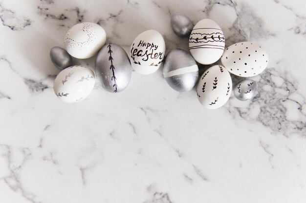 Uova di Pasqua dipinte d'argento e bianche su uno spazio libero della cartolina del fondo di marmo per testo