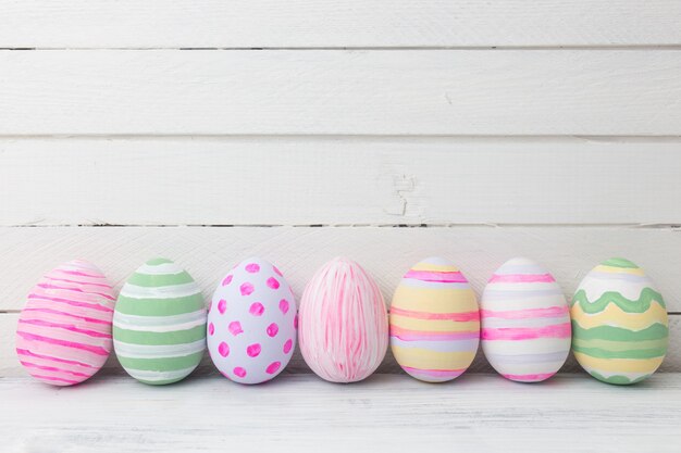 Uova di Pasqua dipinte in colori pastello su fondo di legno bianco. Concetto di Pasqua