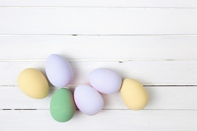 Uova di Pasqua dipinte in colori pastello su fondo di legno bianco