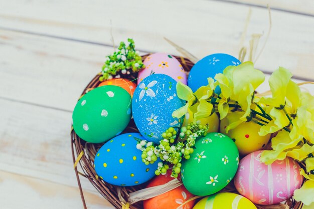 Uova di Pasqua dipinte nei colori pastelli su fondo di legno bianco.