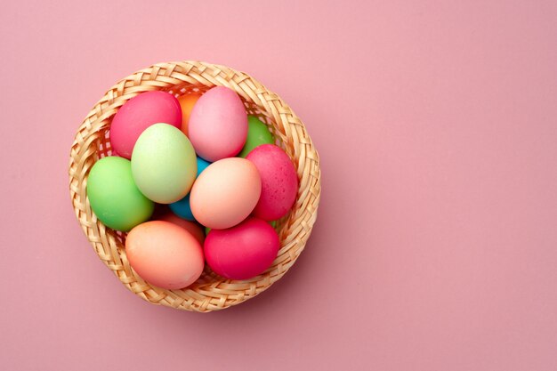 Uova di Pasqua dipinte nel nido decorativo sulla fine rosa del fondo su