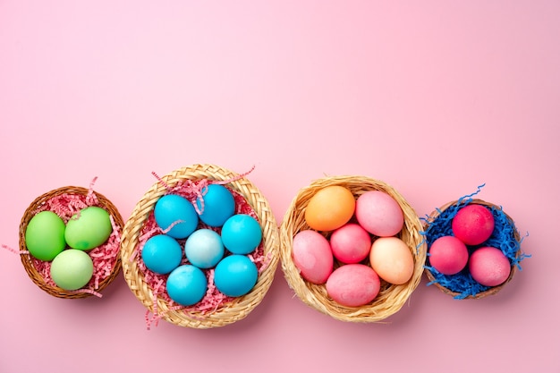 Uova di Pasqua dipinte nel nido decorativo sulla fine rosa su
