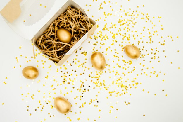 Uova di Pasqua dorate in una scatola con le stelle dorate su fondo bianco