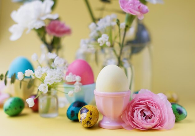 Uova di Pasqua e fiori su sfondo giallo Sfondo di Pasqua con dettagli in colori pastello Concetto di vacanza primaverile