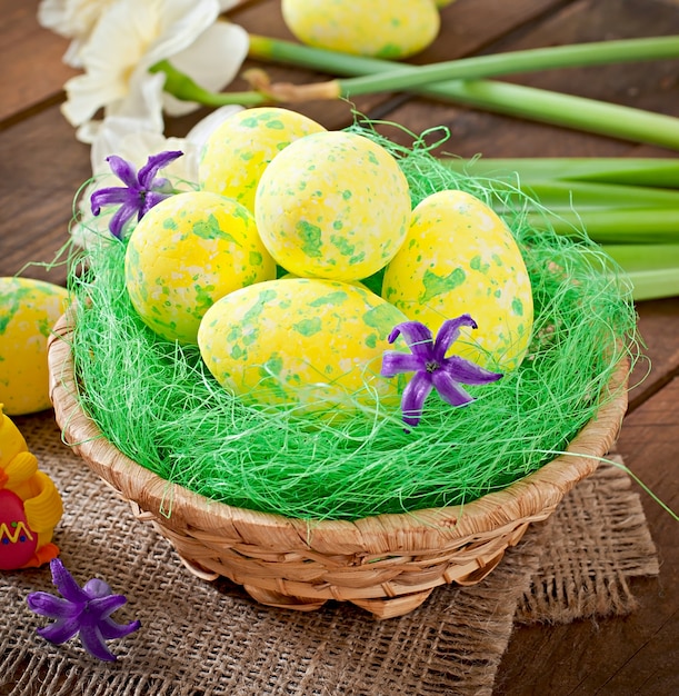 Uova di Pasqua e fiori su superficie di legno