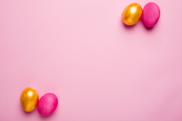 Uova di Pasqua e oro rosa su una superficie rosa