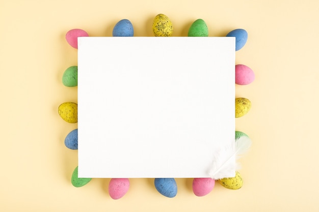 Uova di Pasqua e tela bianca vuota su sfondo pastello